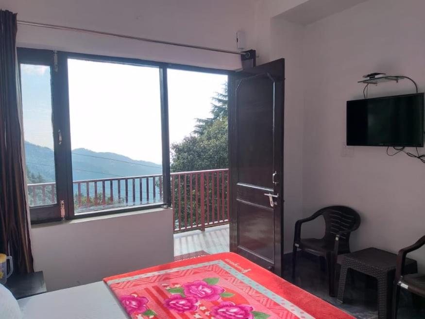 a bedroom with a balcony with a bed and a television at DREAM HILLS B&B in Dalhousie