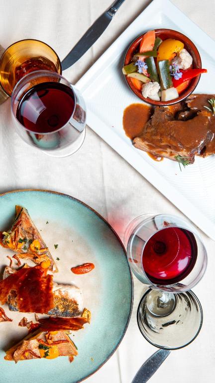 a table with a plate of food and a glass of wine at Albergo della Posta in Astano