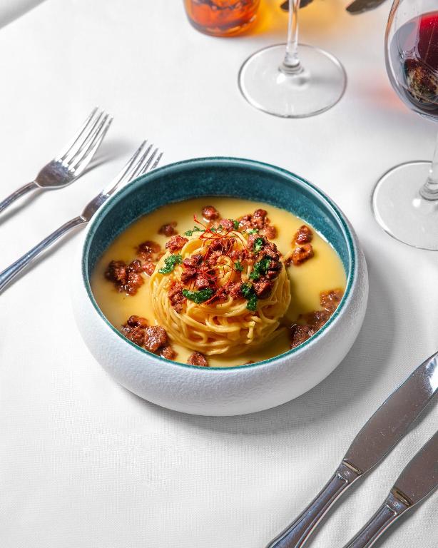 a bowl of soup with pasta on a table at Albergo della Posta in Astano