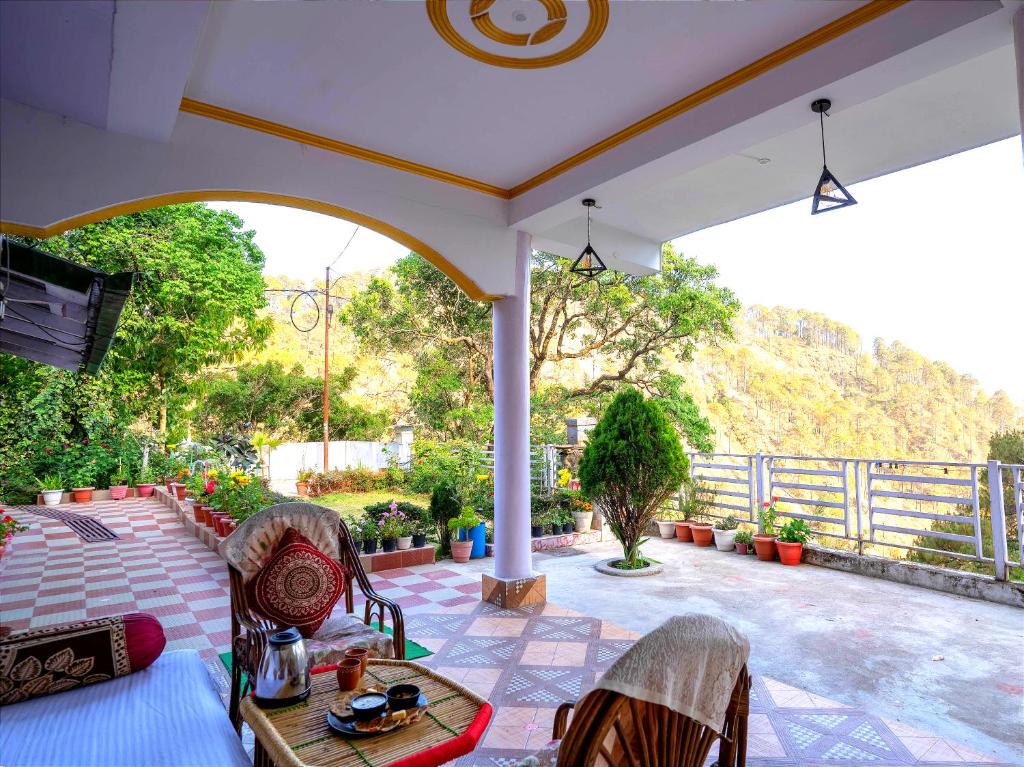 porche con mesa y sillas en el patio en Nature's Vibe Homestay - Nainital - Kainchi Dham, en Nainital