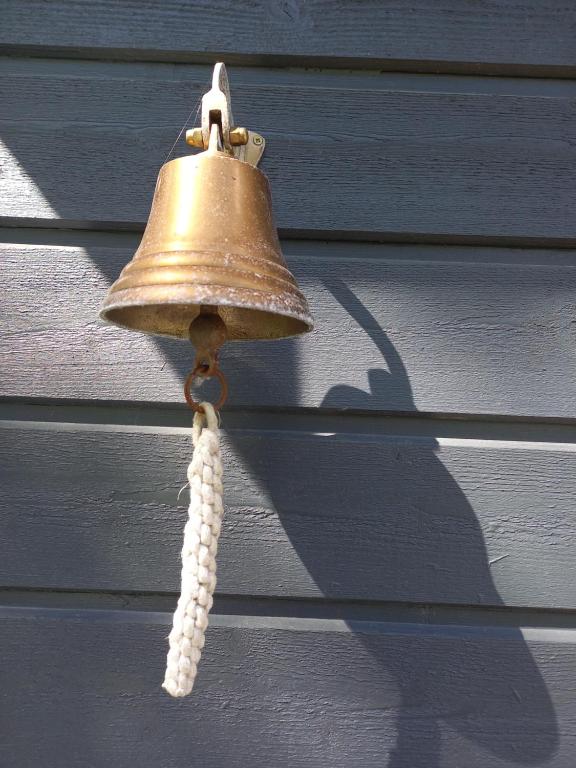 a bell hanging on a blue house with a tassel at Namelis Drevernoje in Dreverna