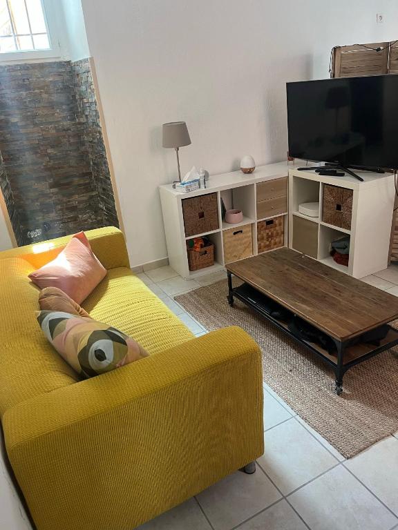 un salon avec un canapé jaune et une table basse dans l'établissement Appartement cosy, à Hyères