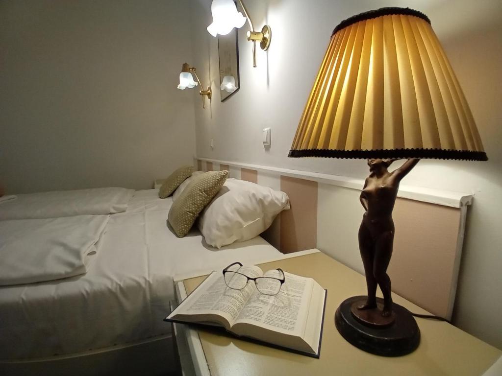 a lamp on a table next to a bed and a book at Senator Ház in Eger