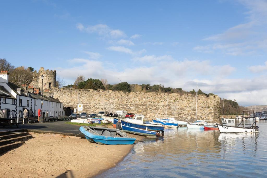 a group of boats docked in the water near a castle at Harbour Cottage, Conwy in Conwy