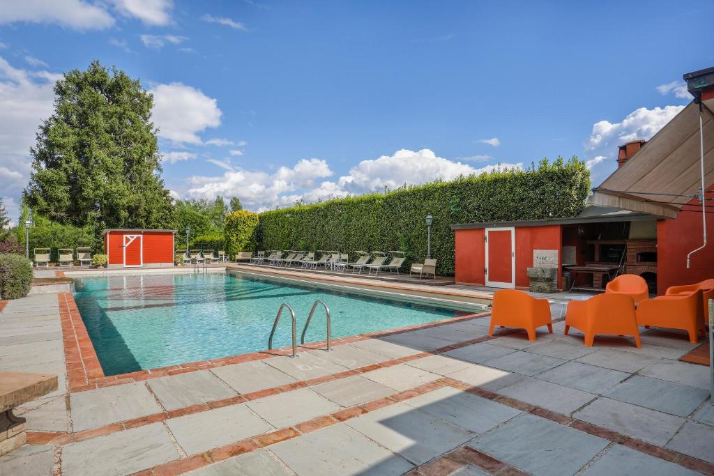 - une piscine avec des chaises oranges à côté d'un bâtiment dans l'établissement POMODORO di Home Hill, à Capannori