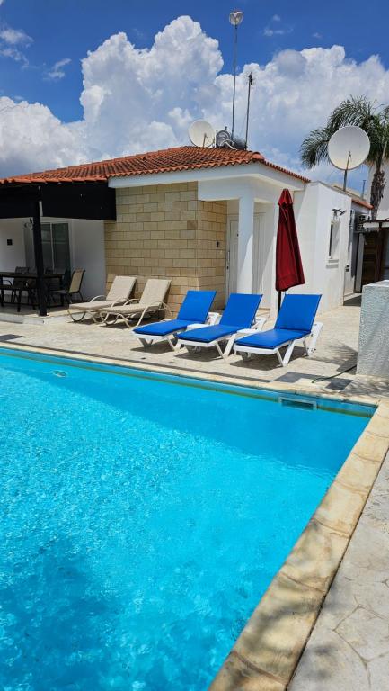 basen z niebieskimi krzesłami i dom w obiekcie Villa Gracia w Ajia Napa