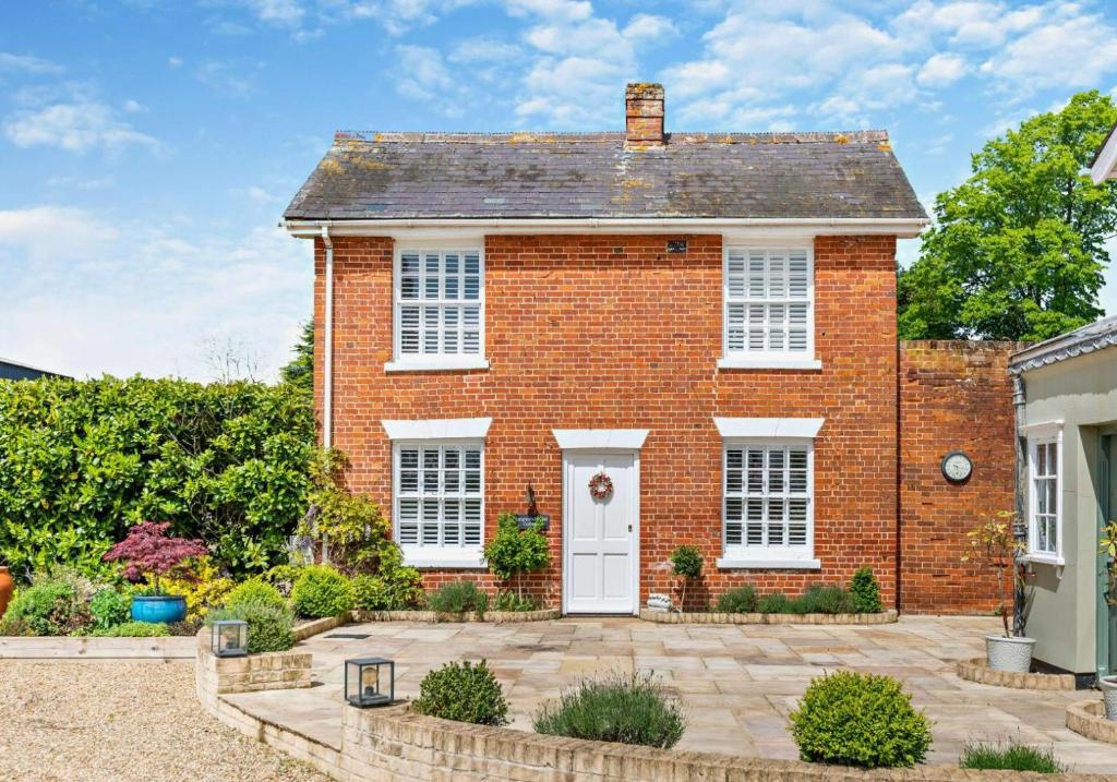 une maison en briques rouges avec une porte blanche dans l'établissement City to Country Retreat Luxury Cottage with Hot Tub, à Toppesfield