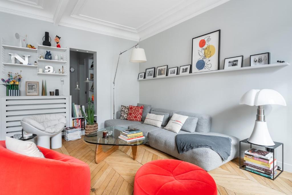 - un salon avec un canapé gris et un fauteuil rouge dans l'établissement Luxe à Boulogne : Appart. Haut Standing, à Boulogne-Billancourt
