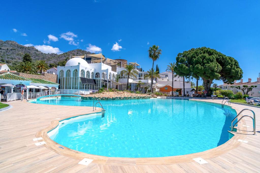 uma grande piscina com água azul num resort em Capuchinos 22 San Juan Capistrano Casasol em Nerja