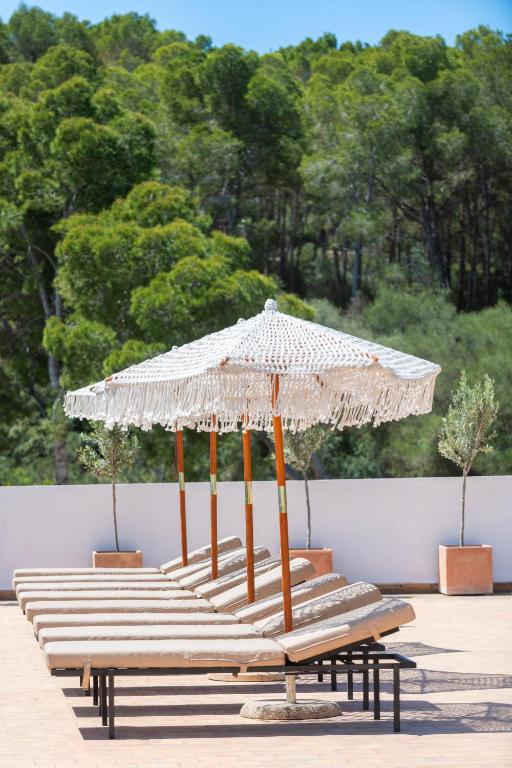 a group of benches with a large umbrella at Hotel Cala Fornells in Paguera
