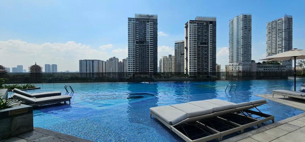 een groot zwembad met stoelen en een skyline van de stad bij Riverside Lumiere Luxury Vacation in Ho Chi Minh-stad