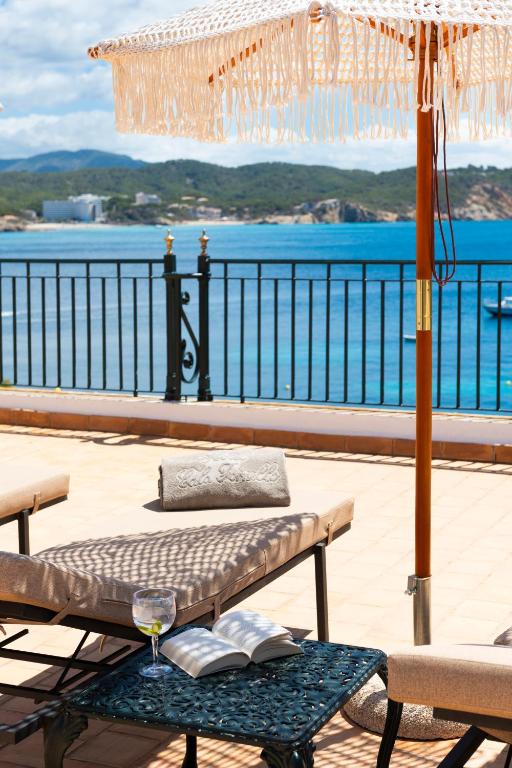 a table with a wine glass and an umbrella at Hotel Cala Fornells in Paguera