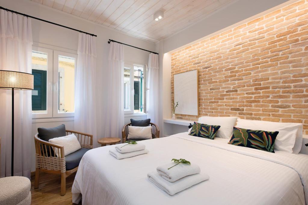 ein Schlafzimmer mit einem großen weißen Bett und einer Ziegelwand in der Unterkunft La Signora Cofineta by Anita Holiday Homes in Korfu-Stadt
