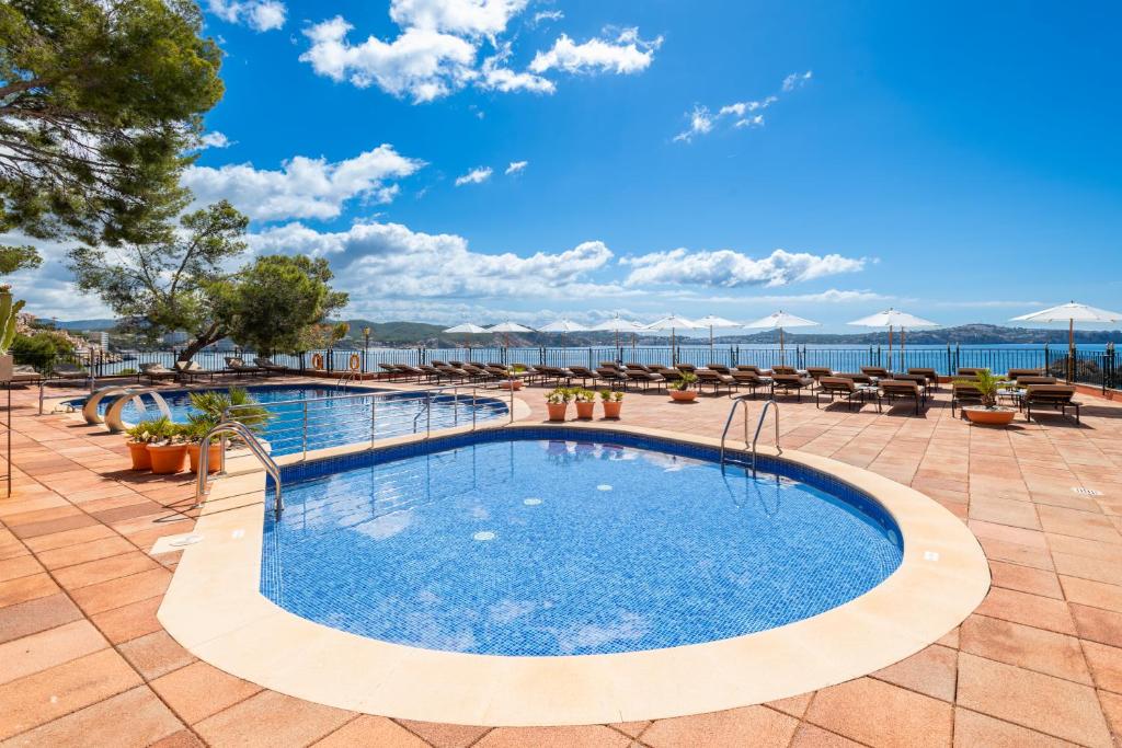 a pool at a resort with the ocean in the background at Hotel Cala Fornells in Paguera