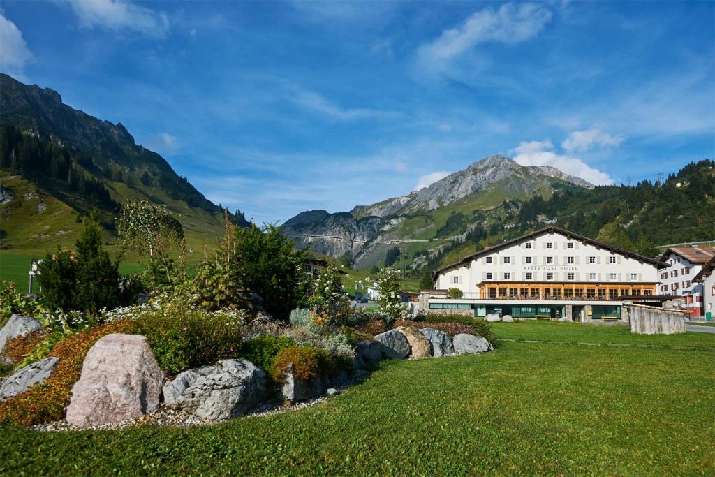 un bâtiment avec un jardin en face d'une montagne dans l'établissement Après Post Hotel, à Stuben am Arlberg