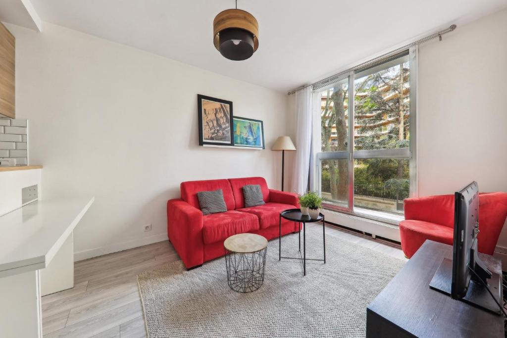 un salon avec des meubles rouges et une fenêtre dans l'établissement Appartement cosy proche porte maillot, à Neuilly-sur-Seine