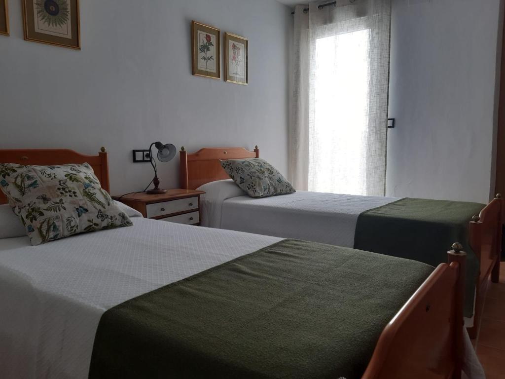 1 dormitorio con 2 camas y ventana en Habitación Higuera, en Lumpiaque