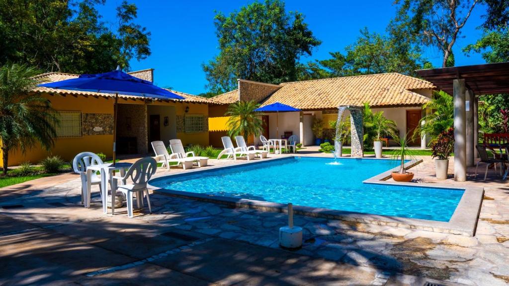 - une piscine avec des chaises et des parasols à côté d'une maison dans l'établissement Recanto 3ELLL, à Bodoquena