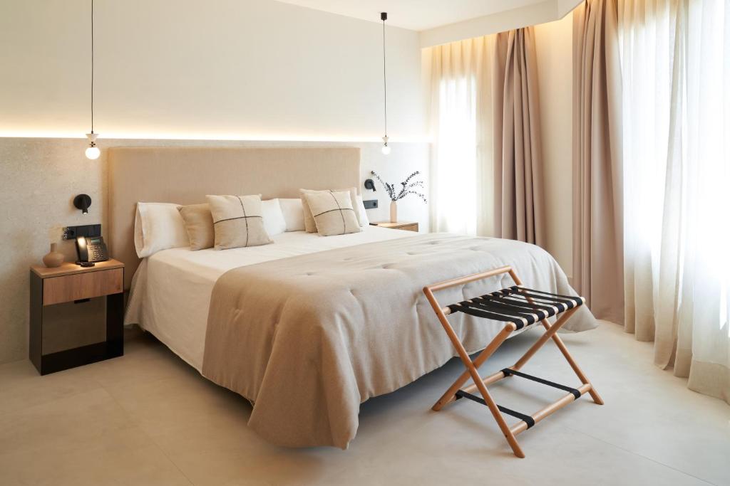 a white bedroom with a large bed and a chair at Hotel-Restaurante Jardines La Tejera in Olula del Río