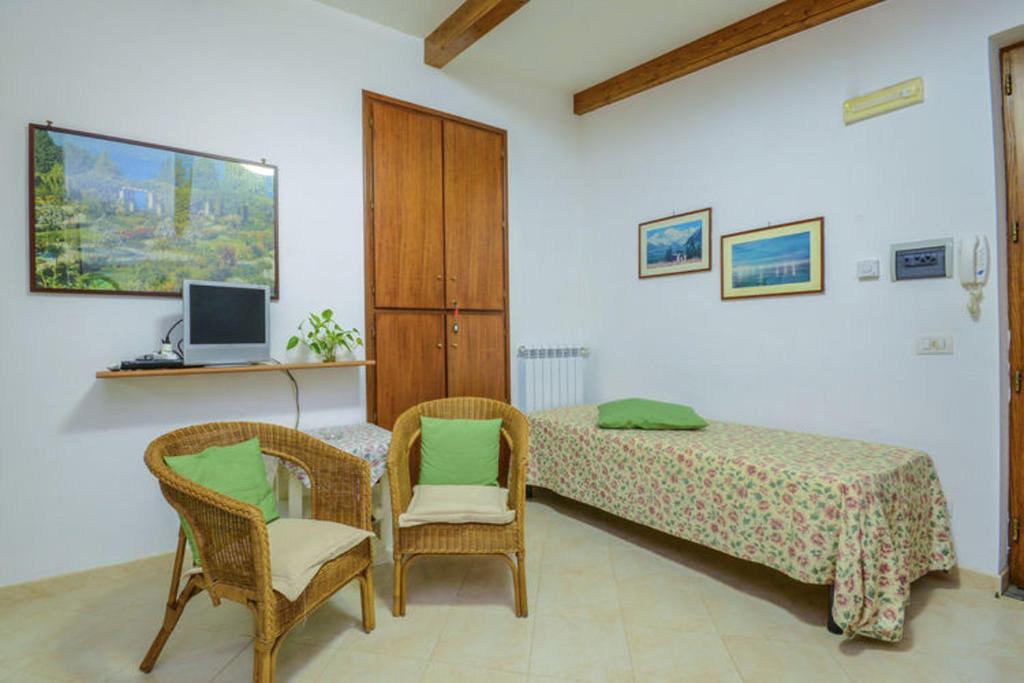 een slaapkamer met een bed en 2 stoelen en een televisie bij One bedroom apartement with sea view enclosed garden and wifi at Sorrento 1 km away from the beach in Sorrento