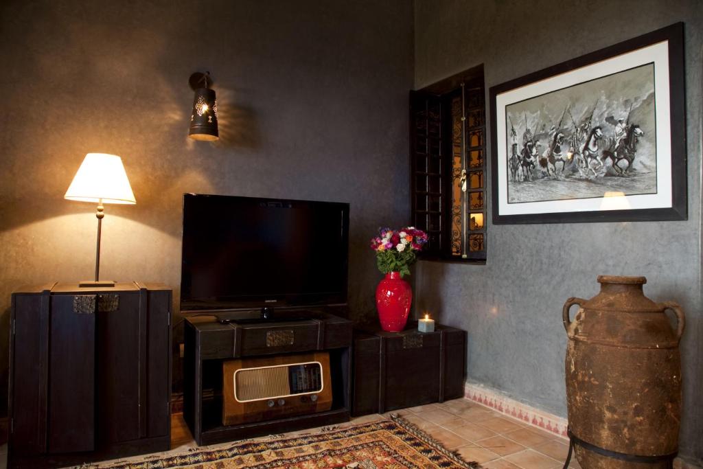 a living room with a television and a vase with flowers at Kasbah Illy in Demnat