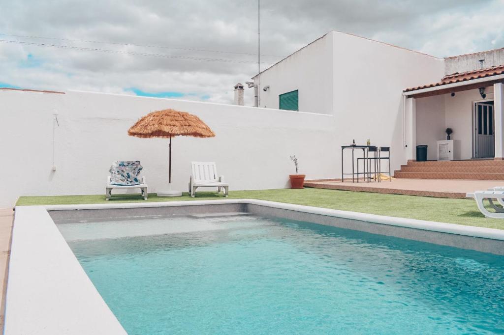 uma piscina com um guarda-sol ao lado de uma casa em Casa da Espiga - Alentejo em Trigaches