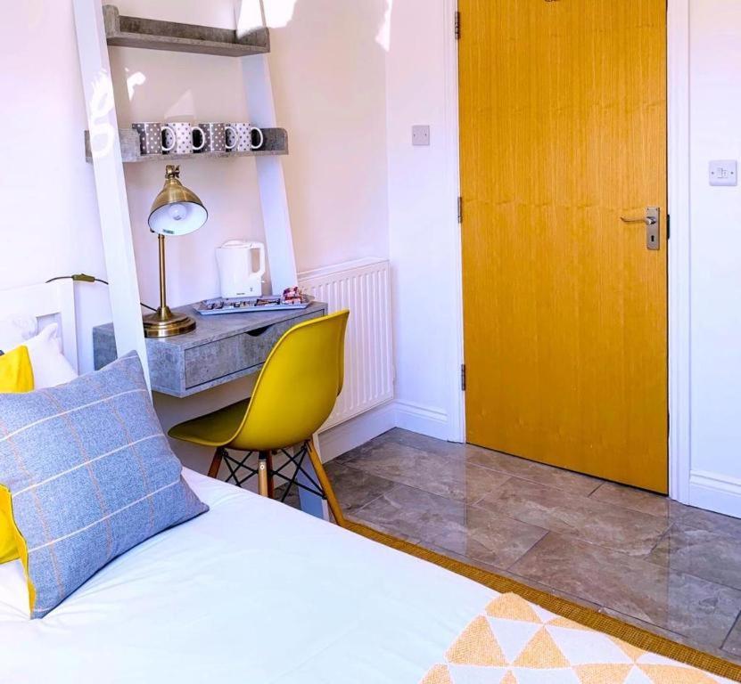a bedroom with a bed and a yellow door and a desk at Room at the Inn in Glastonbury