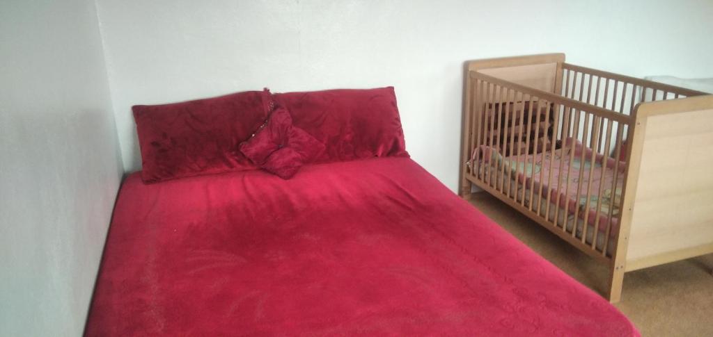 ein Bett mit einer roten Decke neben einem Kinderbett in der Unterkunft Familles avec bébé in Fès