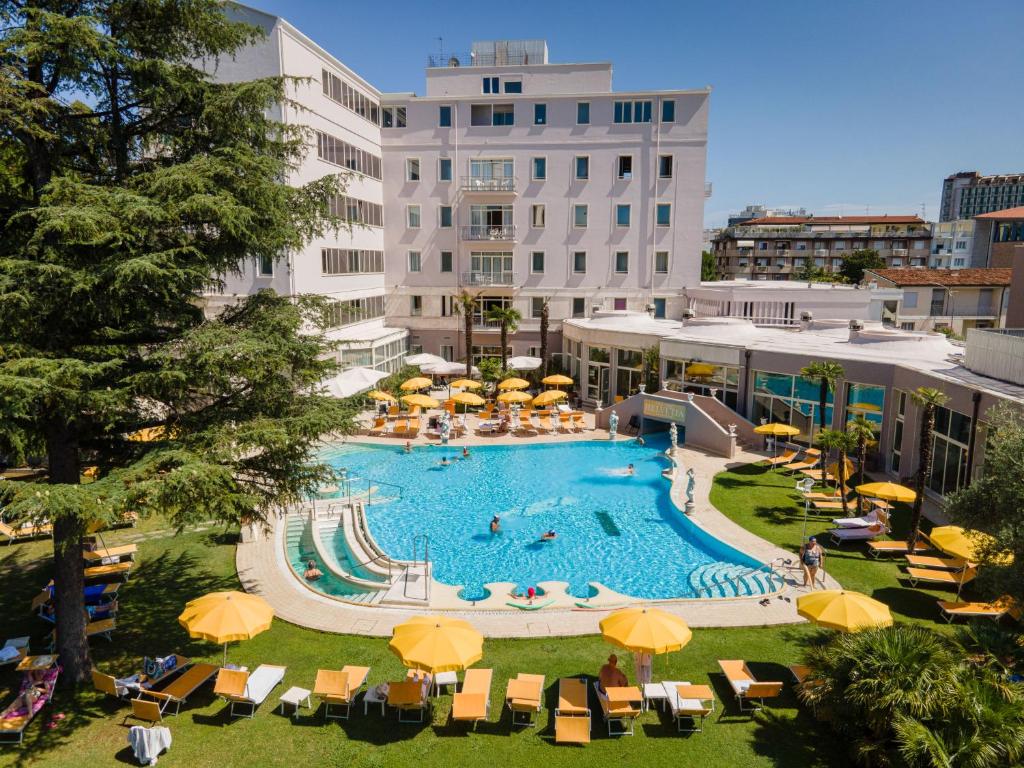 uma grande piscina com guarda-sóis e cadeiras amarelas em Hotel Terme Helvetia em Abano Terme