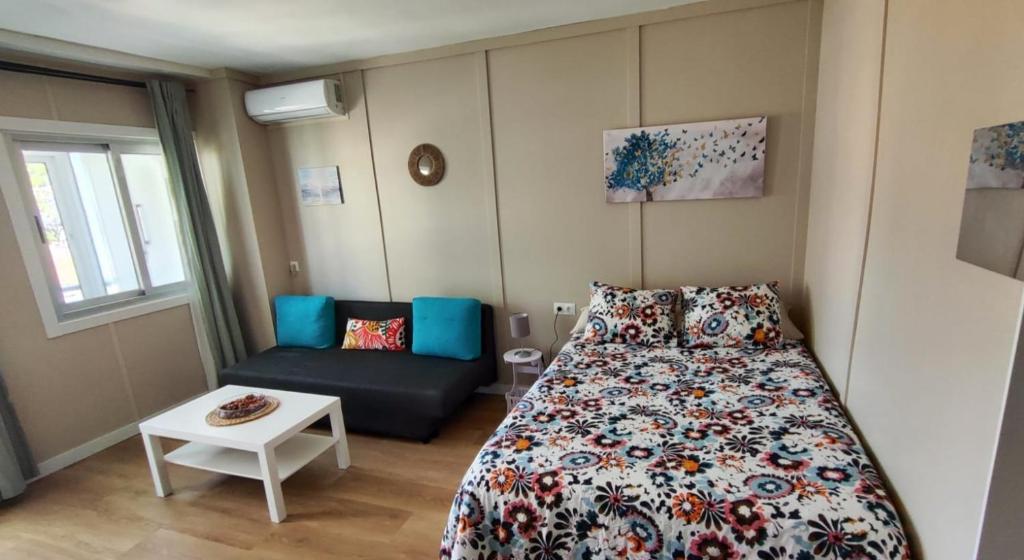 een kleine slaapkamer met een bed en een bank bij Céntrico estudio en Torremolinos in Torremolinos