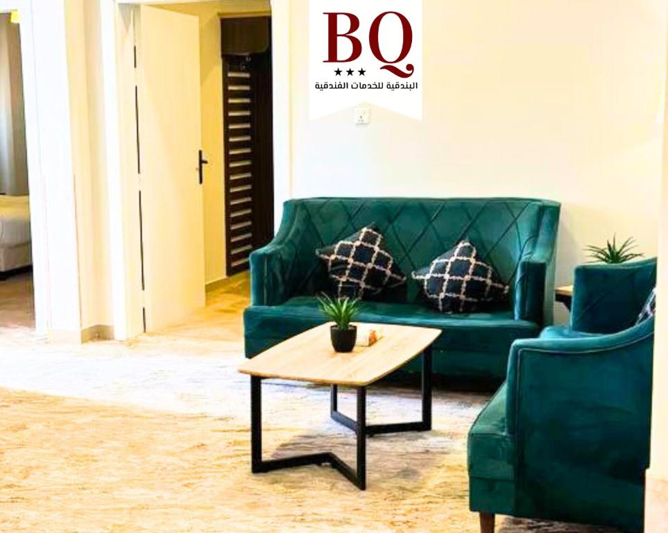 sala de estar con sofá verde y mesa de centro en البندقية للخدمات الفندقية BQ HOTEL SUITES en Buraidah