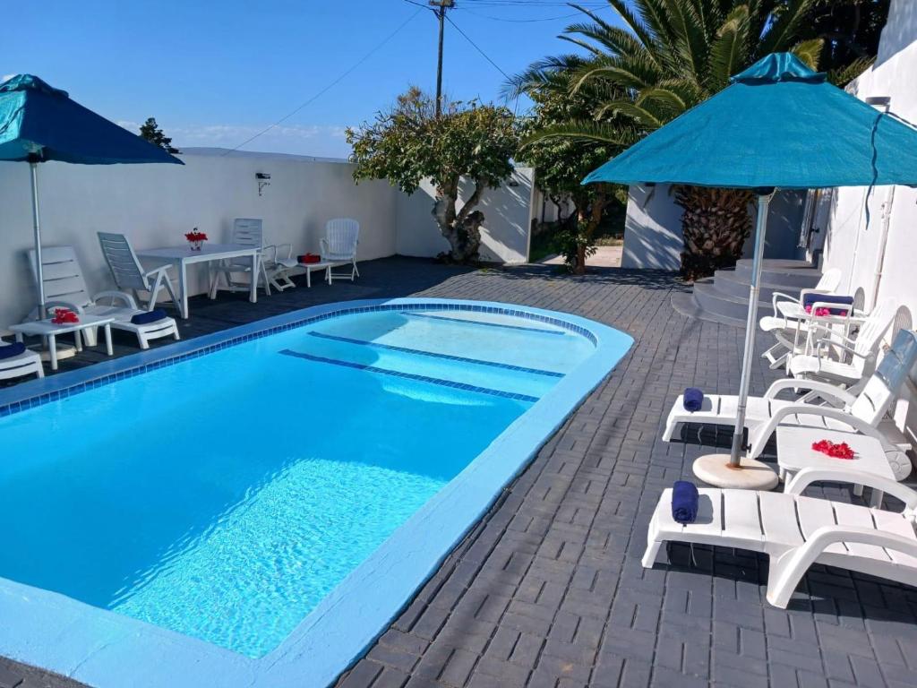a swimming pool with chairs and an umbrella at Saldanha Bay Lodge in Saldanha