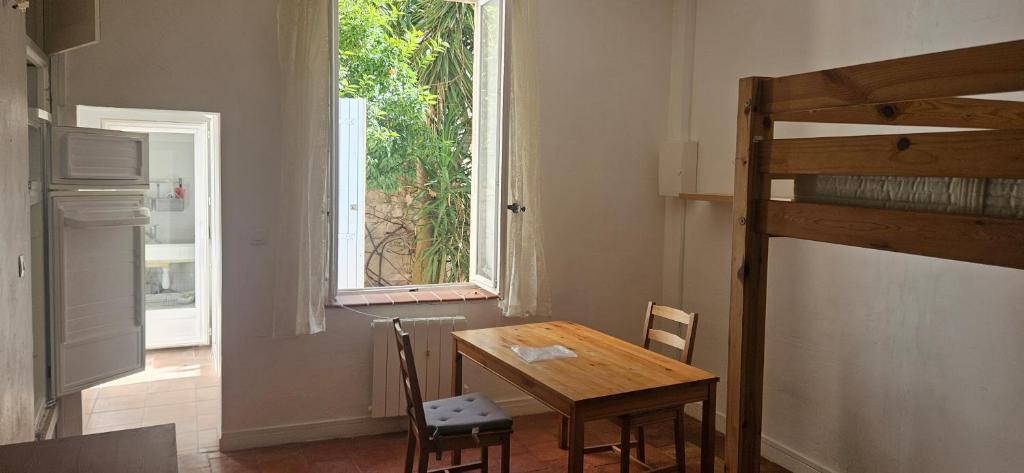 een tafel en stoelen in een kamer met een raam bij Studio entre mer et garrigues in Portel-des-Corbières