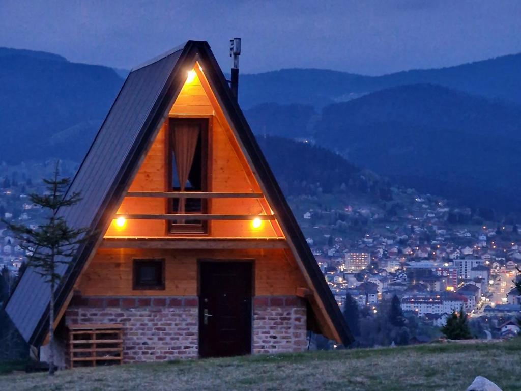 une petite maison en bois avec des lumières sur le toit dans l'établissement Vikendica Tromedja Pale, à Pale