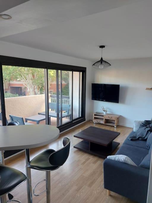 un salon avec un canapé bleu et une table dans l'établissement Appartement de charme au coeur de Perpignan, à Perpignan