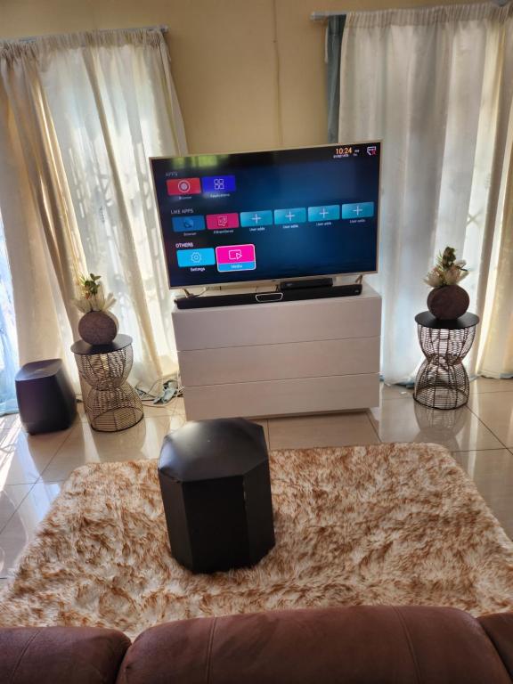 ein Wohnzimmer mit einem großen Flachbild-TV in der Unterkunft Dollar Zone in Manzini