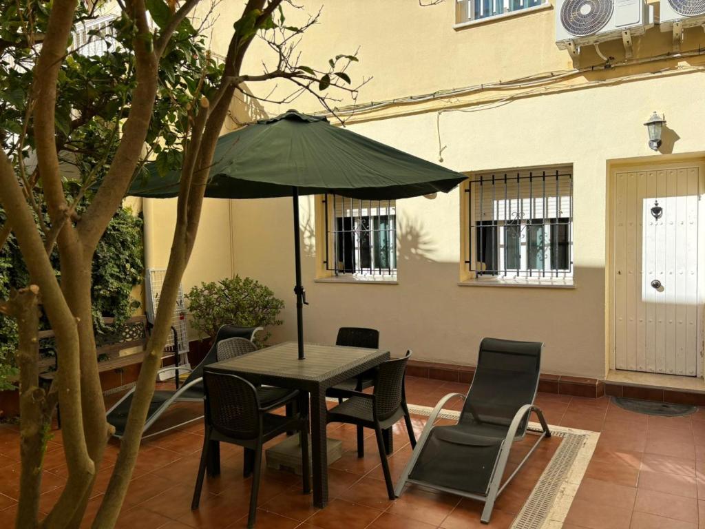 una mesa con sillas y una sombrilla en el patio en Hospederia Imar, en Cádiz