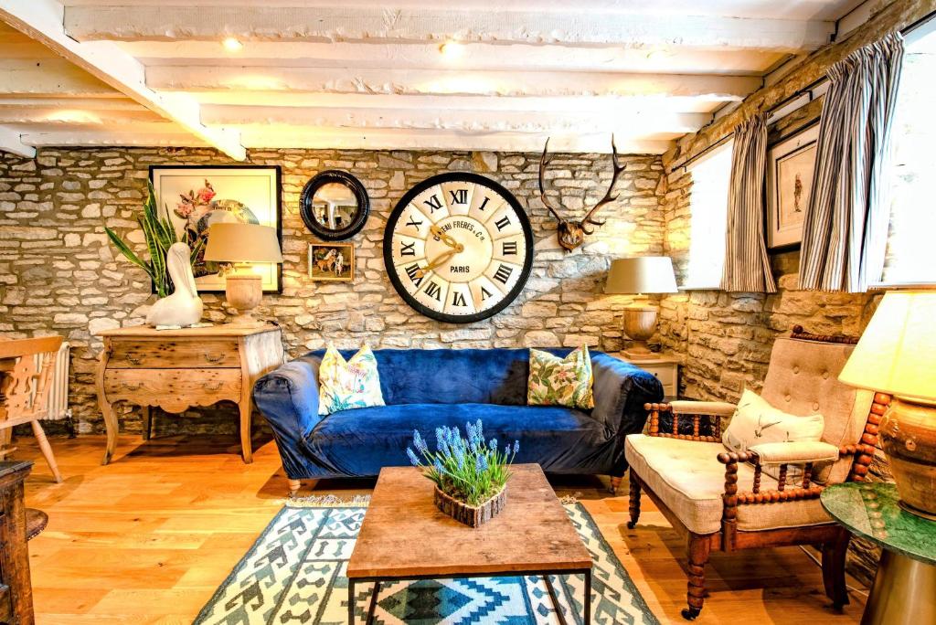 a living room with a blue couch and a clock on the wall at Cosy Little Hyde Cottage, Swanage in Swanage