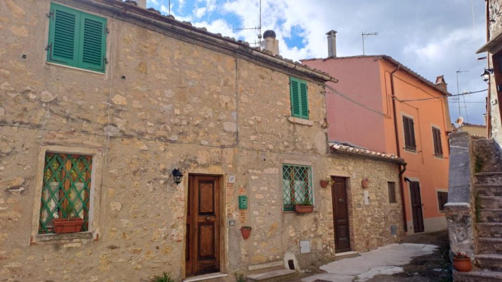 センプロニアーノにあるla casina della bubbolinaの古い石造りの建物で、カラフルな窓とドアが特徴