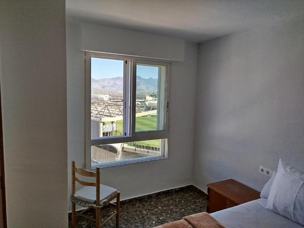 Habitación con cama, silla y ventana en ushuaia, en Castellón de la Plana