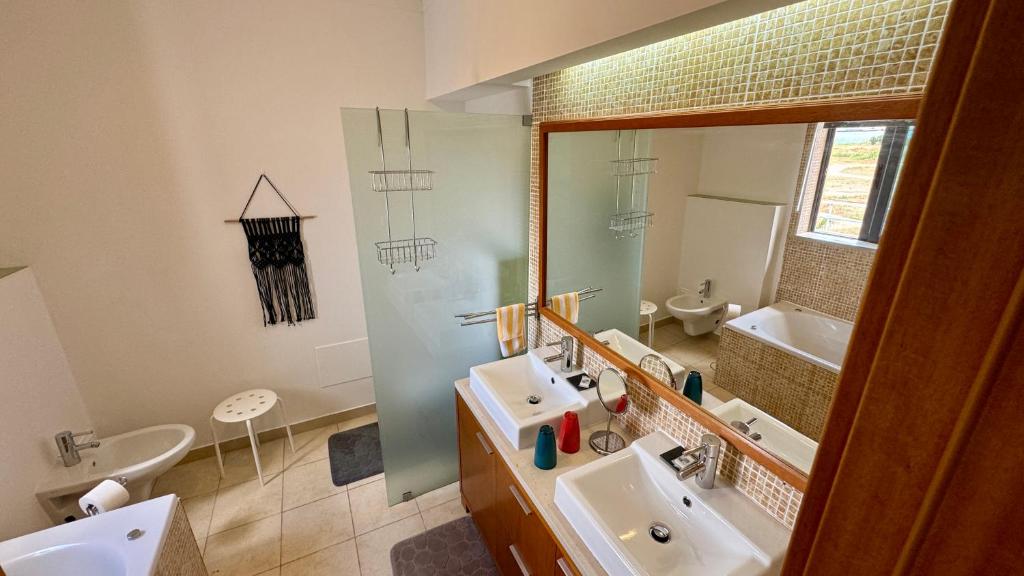 La salle de bains est pourvue de 2 lavabos, d'un miroir et d'une baignoire. dans l'établissement Casa "Vento" Ferragudo mit privatem Pool, à Ferragudo