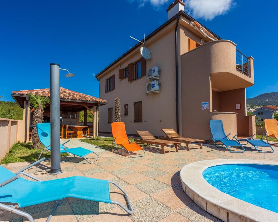 a villa with a pool and chairs and a house at Family house with swimming pool in Novi Vinodolski