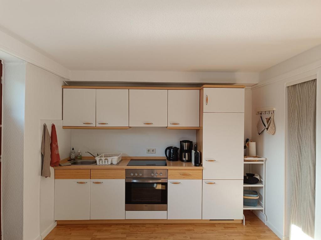 a kitchen with white cabinets and a stove at Appartement Plögemaker in Süsel