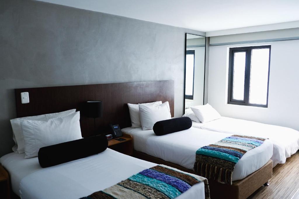 a hotel room with two beds and a mirror at Hotel DC Feria in Bogotá