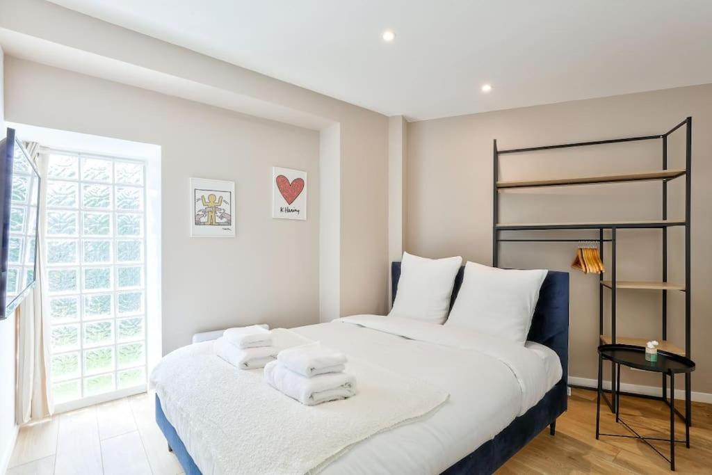une chambre blanche avec un lit avec des serviettes dessus dans l'établissement Charme Parisien 4 Personnes, 1 chambre, 19ème, à Paris