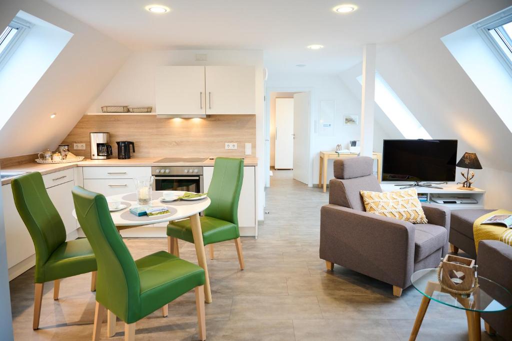a kitchen and living room with a table and green chairs at Haus Burgsponheim in Burgsponheim