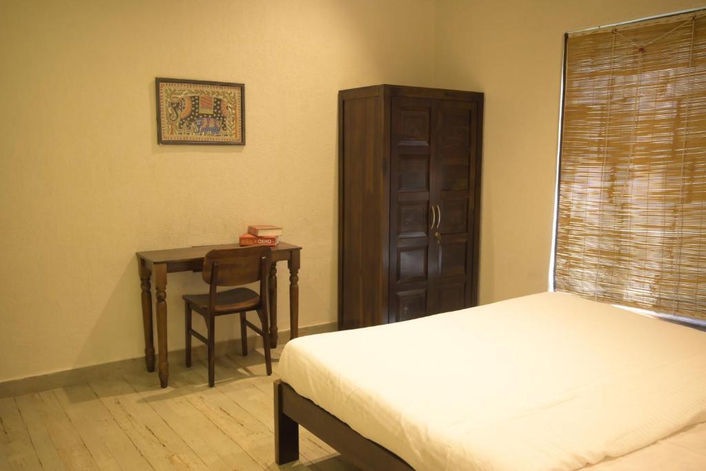 Tattvamasi Retreat في مومباي: غرفة نوم بسرير ومكتب وطاولة