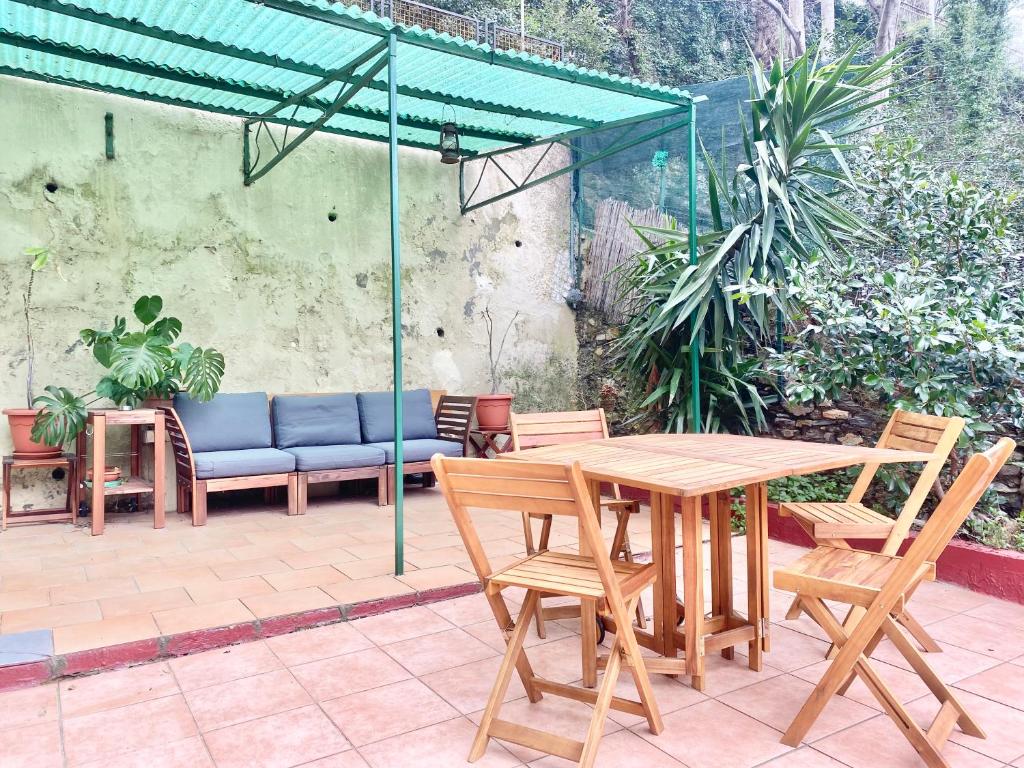 drewniany stół i krzesła pod zielonym parasolem w obiekcie CasaViva - Bilo with patio in Genova San Teodoro w Genui
