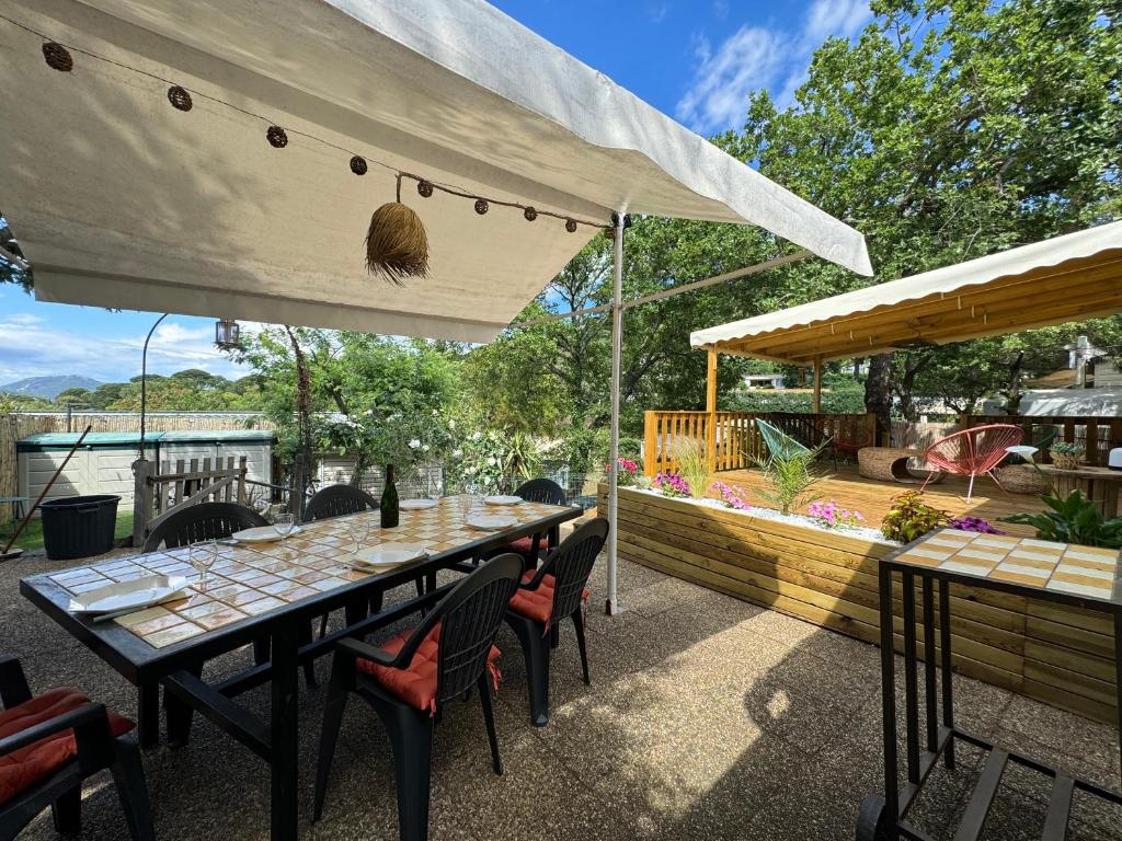 un patio avec une table et des chaises sur une terrasse dans l'établissement Mobil home climatisé golf de saint tropez camping 4 étoile, à Gassin