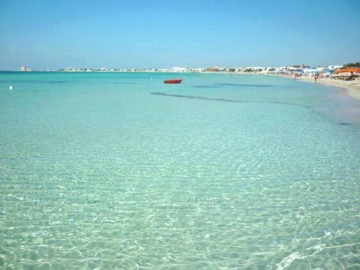 a beach with a red boat in the water at Villa Aurora 1 in Torre Lapillo